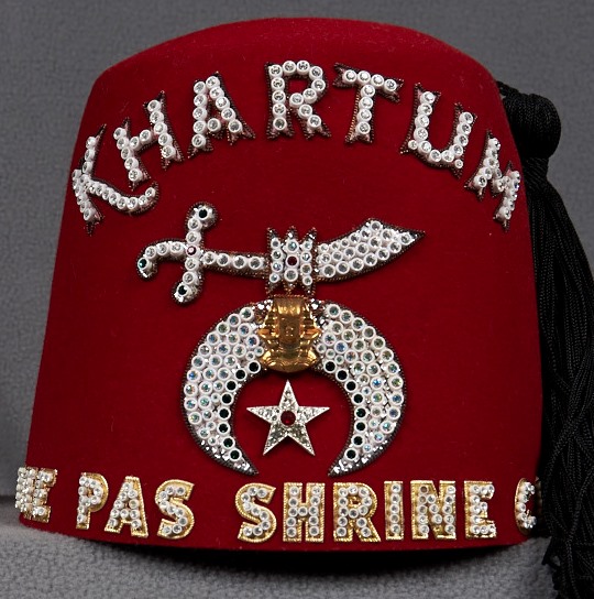 The 'Fez' hat of the Masonic 'Shriners', which originated in the city of Fez, Morocco, where 50 000 Christians were massacred by Muslims. The Shriners wear that same red fez today, with the Islamic sword and crescent encrusted with jewels on the front. Photo credit: Sam Waller Museum, www.digitalmuseums.ca